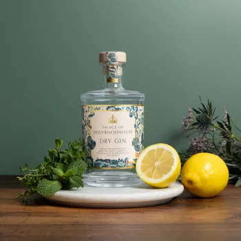 Photograph of a bottle of the Palace of Holyroodhouse Dry Gin surrounded by fresh lemons and herbs